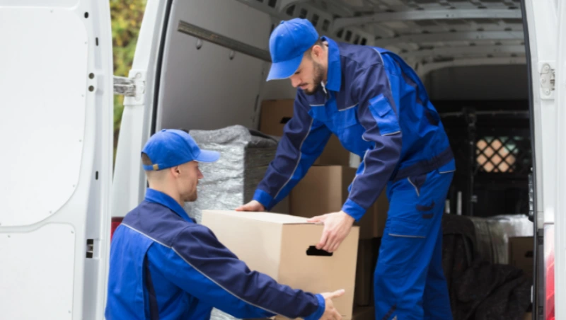 Two movers handling fragile wrapped items inside moving van with care