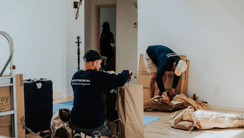 Villa Movers in Dubai team unpacking and arranging wrapped furniture in new home interior