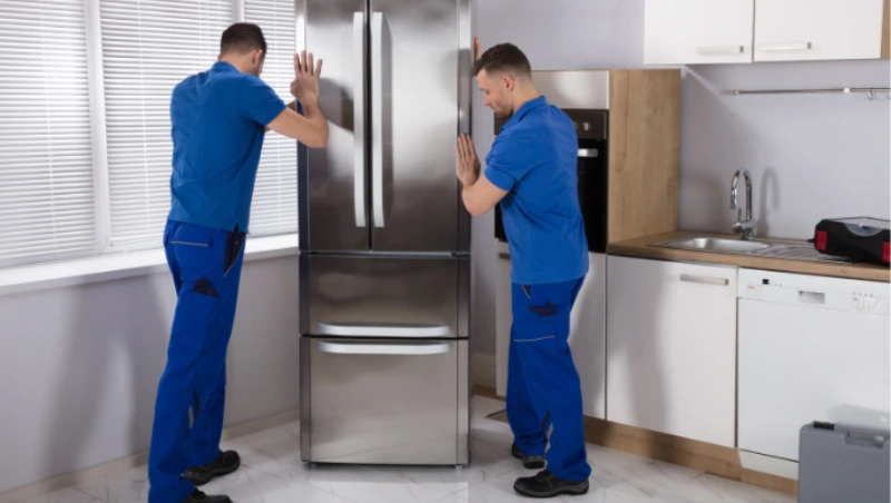 Two technicians discussing utility appliance installation in residential kitchen